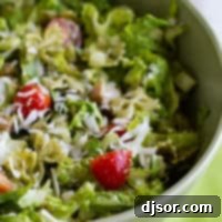 Pesto Pasta with Ham Salad 4 Bowl filled with pesto pasta and ham salad with romaine and tomatoes.