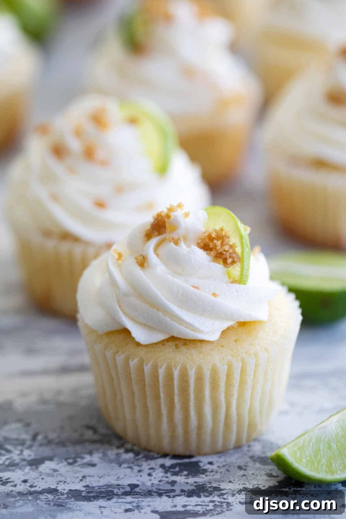 An assembled Key Lime Cupcake garnished with golden graham cracker crumble, showcasing its perfect piping of buttercream and inviting texture.