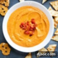 Smoky Roasted Red Pepper Hummus 2 Bowl of roasted red pepper hummus surrounded by pitas, pita chips, and pretzels.