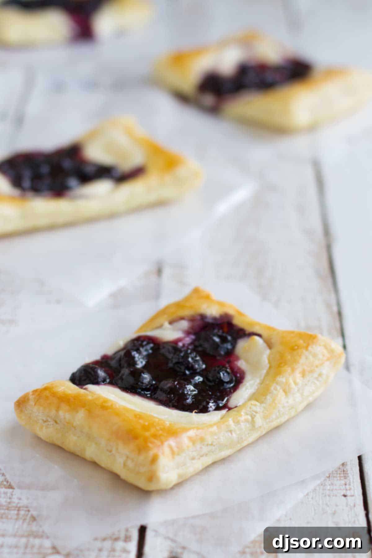 Crispy puff pastry rectangles topped with a rich cream cheese filling and a glistening blueberry mixture, ready to bake.