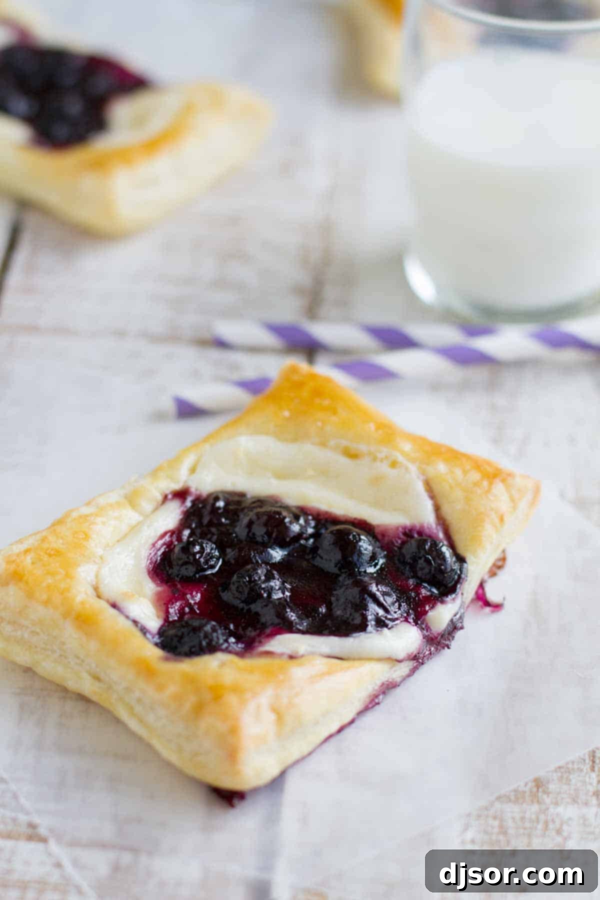 Freshly baked danishes on a cooling rack, showcasing their puffed golden crusts and vibrant fruit filling.