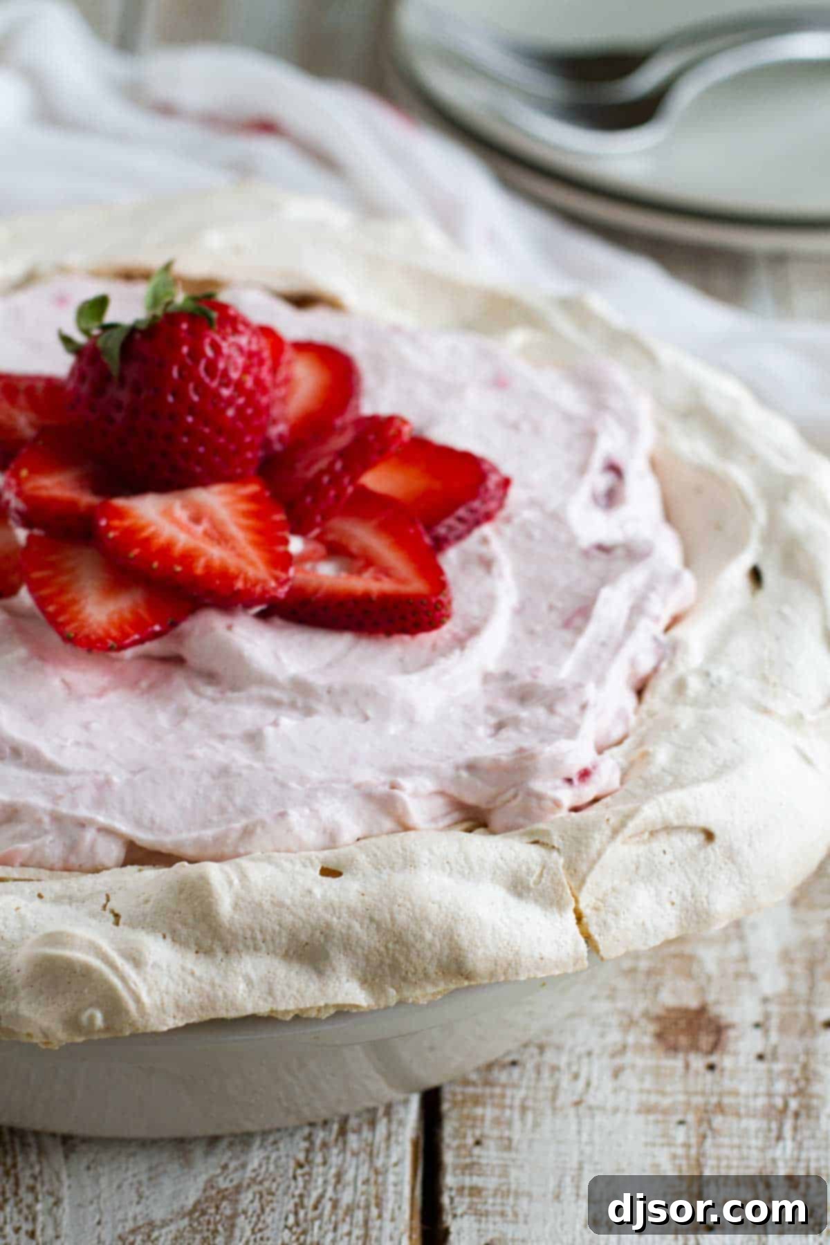 Whole Strawberry Cream Angel Pie Whole Strawberry Cream Angel Pie generously topped with fresh, vibrant strawberries, sitting on a rustic wooden surface, ready to be served. The meringue crust is visible around the edges.