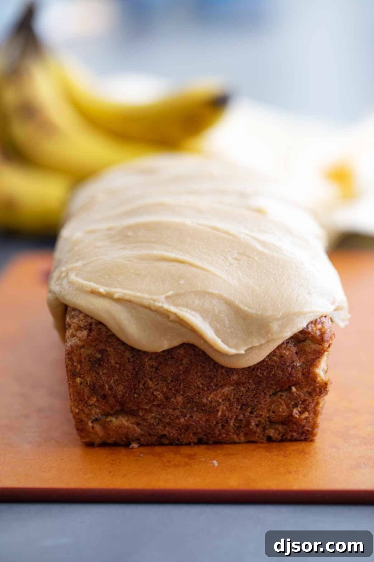A close-up of a slice of banana bread beautifully coated with rich caramel icing, ready to be enjoyed, showcasing the moist interior.