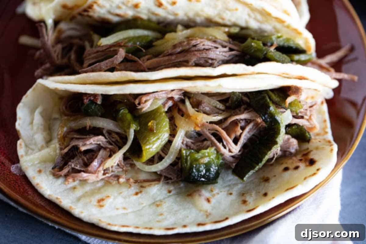 The finished masterpiece: mouthwatering brisket tacos ready to be devoured. Brisket Tacos with poblano peppers and onions, served on flour tortillas.