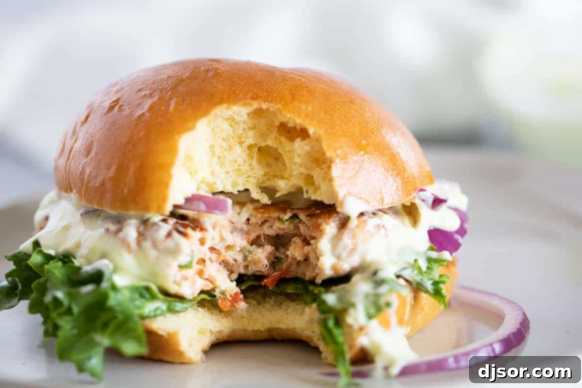 Close-up of a Salmon Burger with a bite taken out, showing the delicious interior and toppings