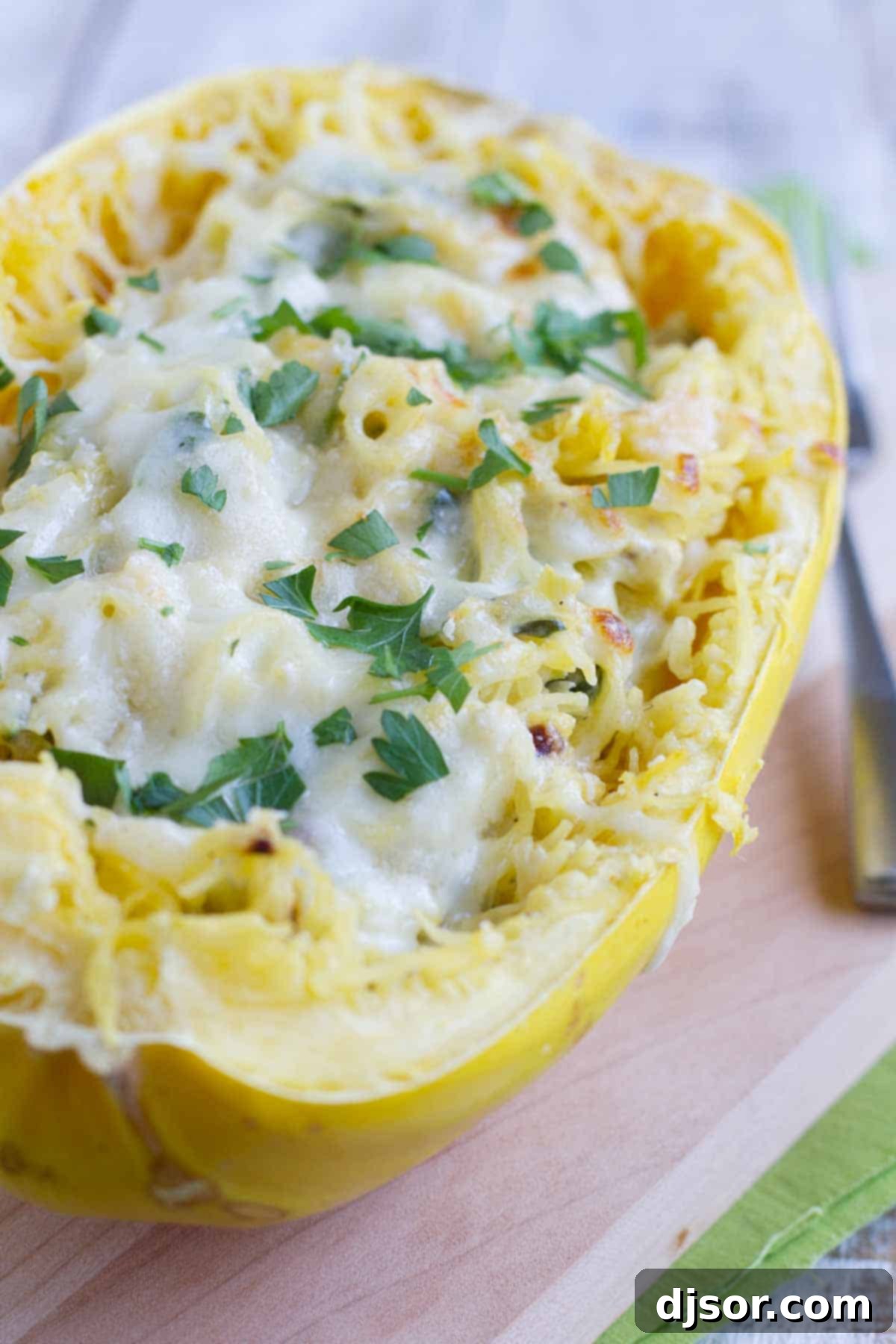 A beautifully presented Spinach Artichoke Spaghetti Squash topped with melted cheese, served in its own shell for an inviting, rustic touch. This healthier take on a classic dip is perfect for a light yet satisfying meal.