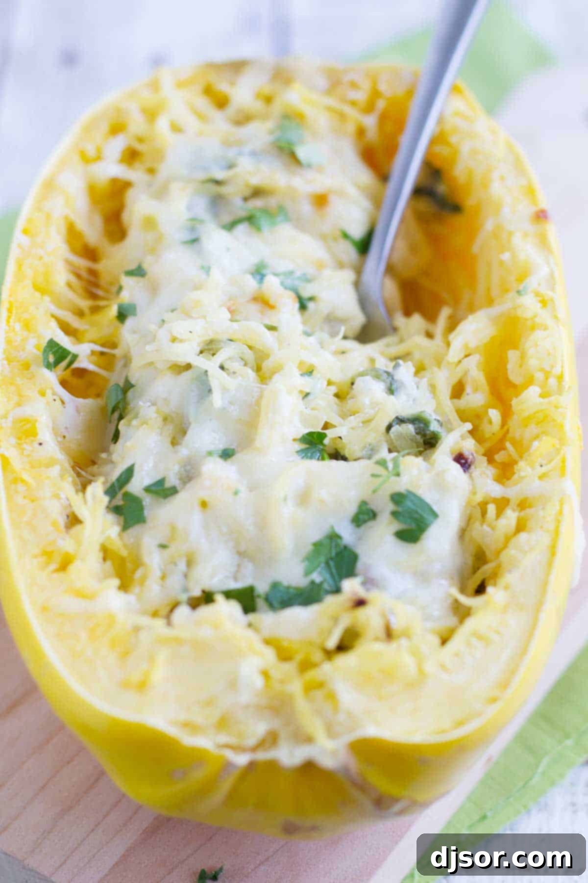 A close-up view of spaghetti squash filled with a creamy, cheesy spinach and artichoke mixture, highlighting the vibrant ingredients and inviting texture.