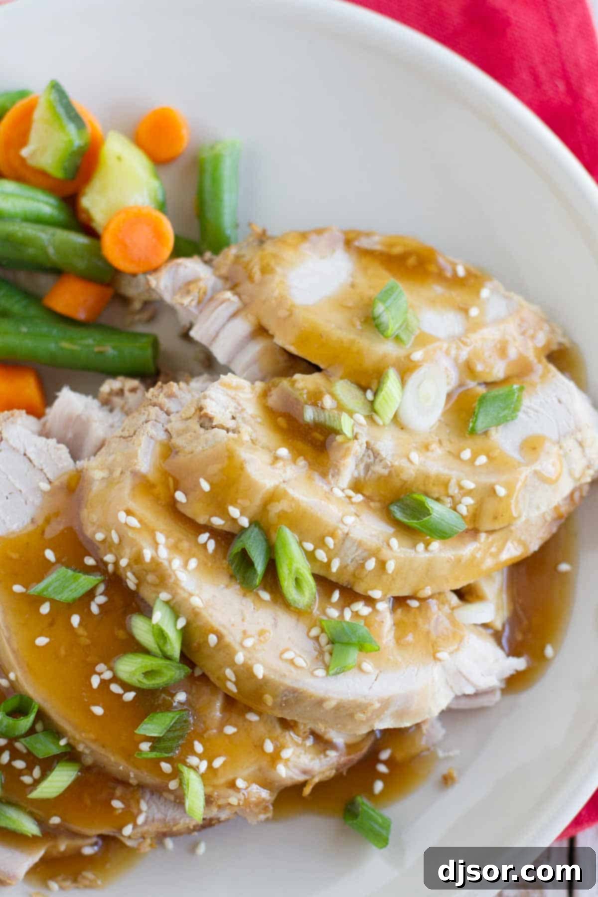 Slow Cooker Sesame Pork topped with sauce, green onions, and sesame seeds.