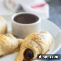 Fluffy Breakfast Sausage Rolls 8 Breakfast Pigs in a Blanket on a plate with maple syrup for serving.