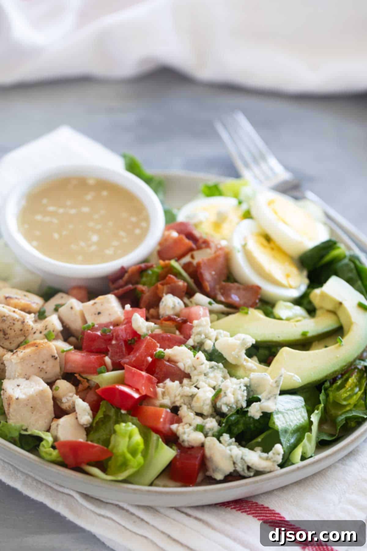Cobb Salad on a plate with ramekin of dressing on the plate.