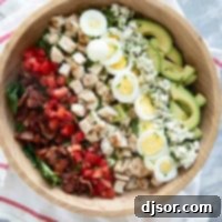 Cobb Salad with toppings arranged in lines on top in a large bowl.