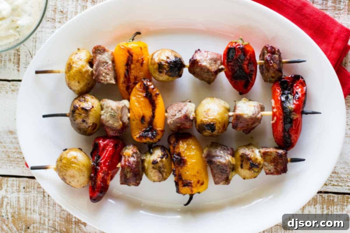 Close-up of vibrant grilled kabobs featuring steak, potatoes, and colorful peppers.