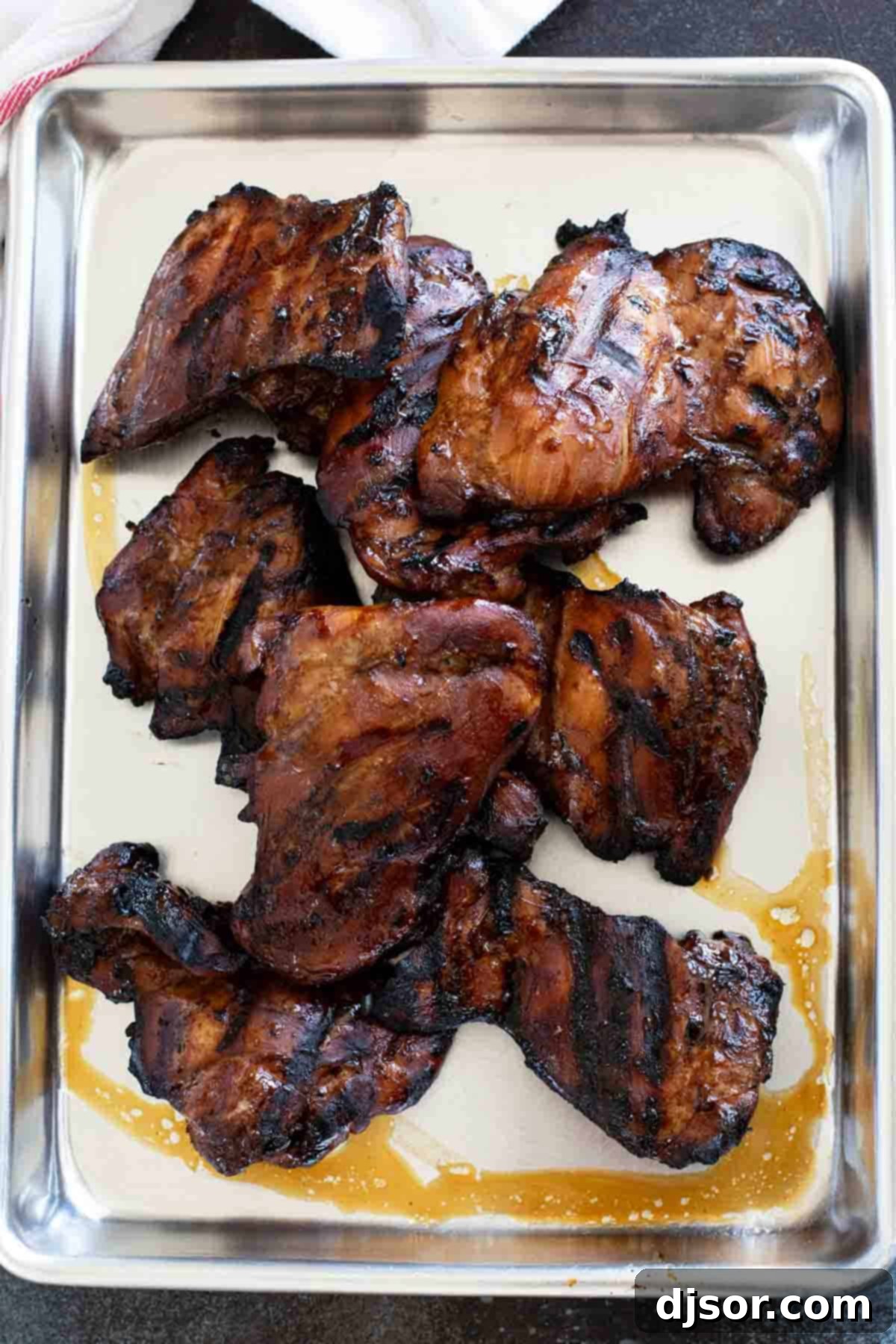 Sticky Honey Soy Glazed Chicken 5 Beautifully grilled Honey Soy Chicken resting on a baking sheet, showcasing its golden-brown glaze.
