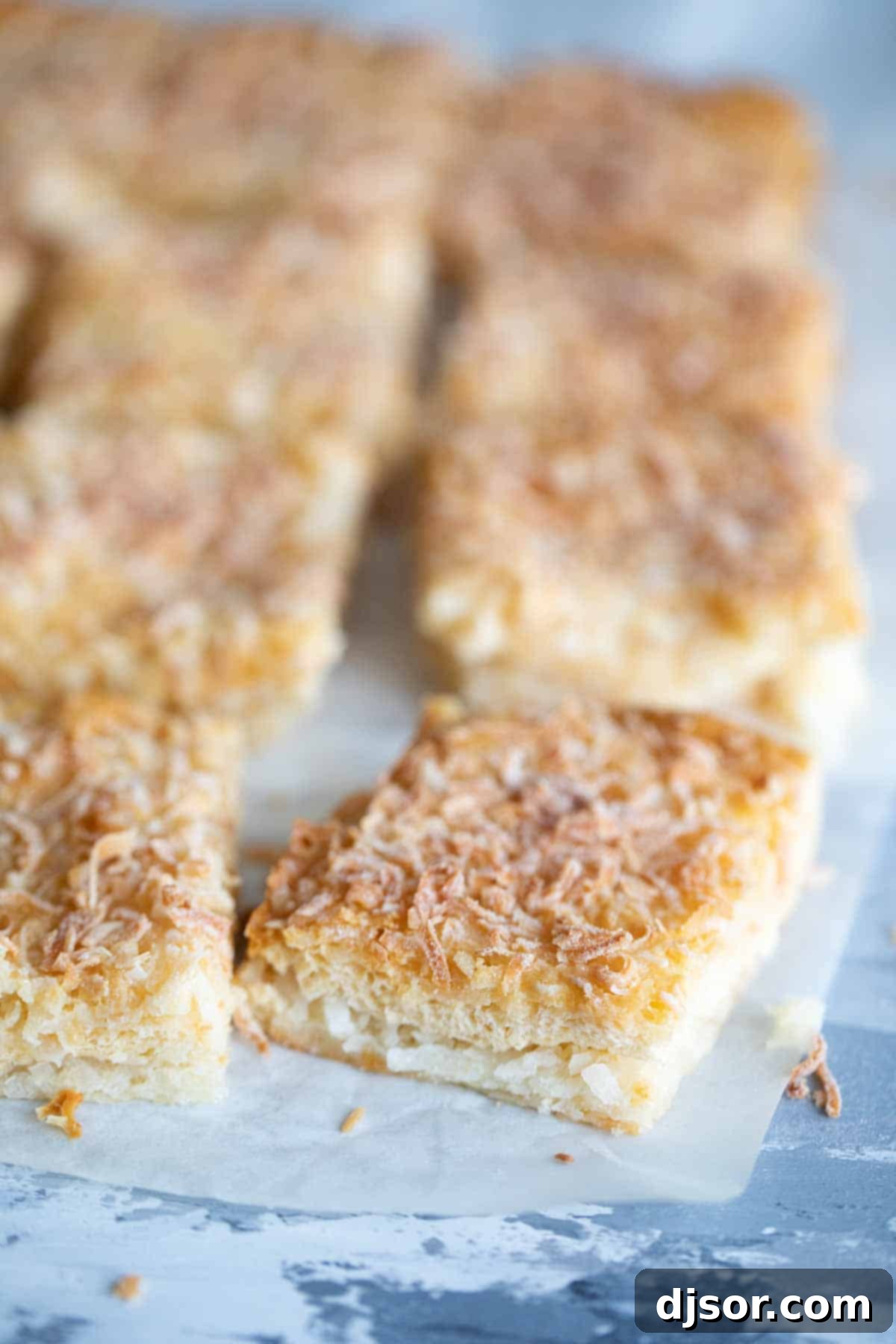 Perfectly cut and ready-to-eat coconut bars Cut coconut bars displayed on a piece of parchment paper, showing their soft texture