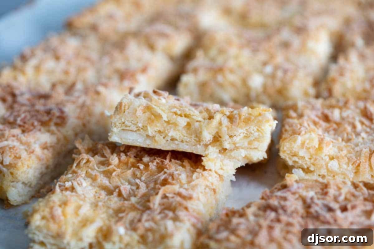 Stacked coconut bars showcasing their delectable layers Stack of coconut bars showing the delicious layers and texture from the side