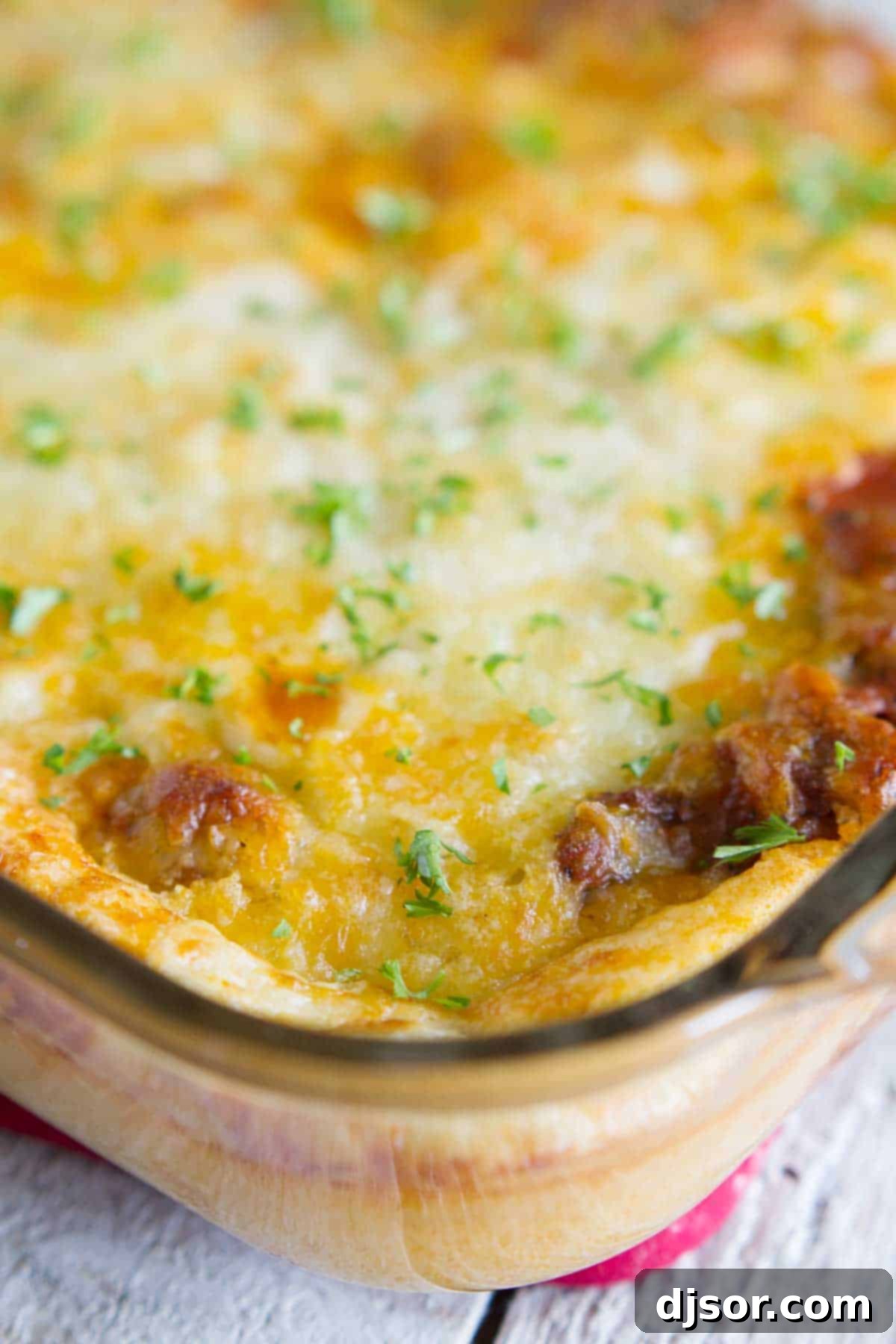 A close-up of Puffed Up Pizza Casserole, showcasing its golden, airy dough topping and rich, cheesy filling, perfect for a cozy meal. Puffed Up Pizza Casserole in a glass baking dish, golden brown and bubbling, ready to be served as a comforting family dinner.