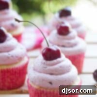 Almond cupcakes topped with fresh cherry frosting with a fresh cherry on top