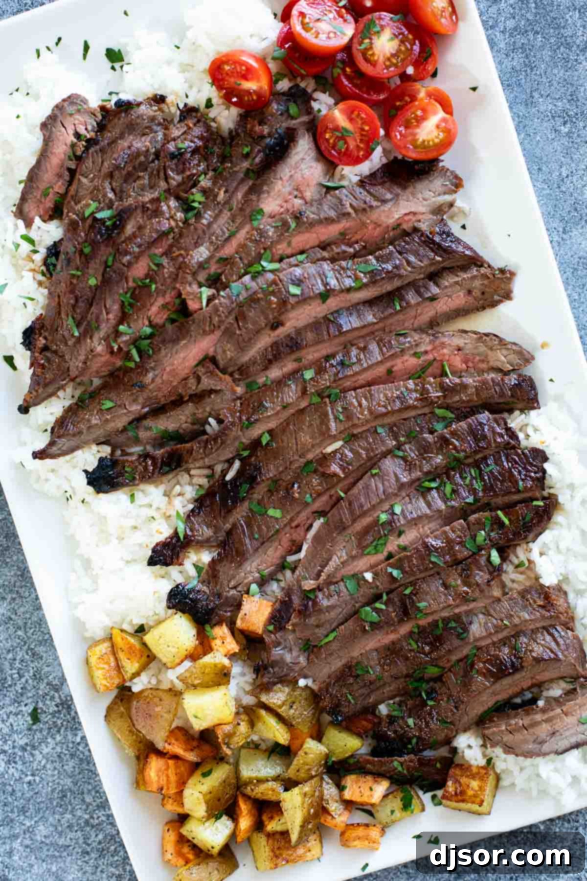 Grilled Korean Flank Steak, thinly sliced and served over fluffy white rice on an elegant serving platter, garnished with sesame seeds and green onions.