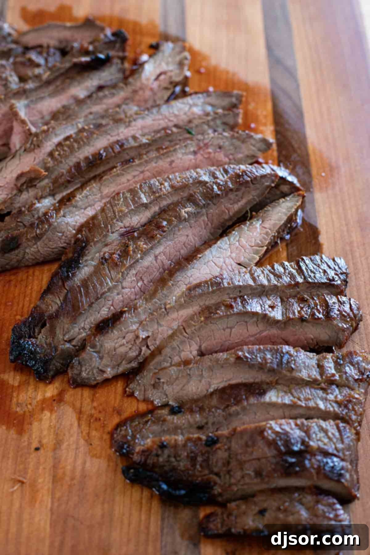 Perfectly grilled Korean Flank Steak resting on a wooden cutting board, skillfully cut into thin, tender slices against the grain, ready to be served.