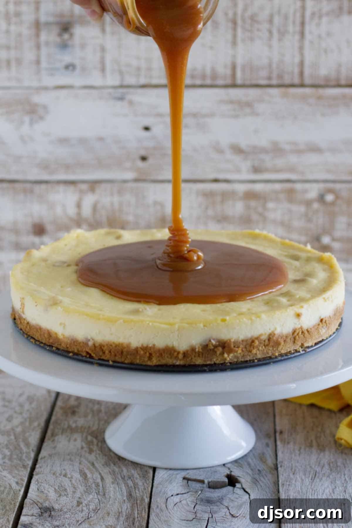 White Chocolate Cheesecake with Macadamia Nuts and Caramel - Creamy white chocolate cheesecake has macadamia nuts throughout, with a homemade caramel sauce poured over the top. Golden, homemade caramel sauce being artfully poured over a freshly baked white chocolate cheesecake, promising a layer of rich sweetness.