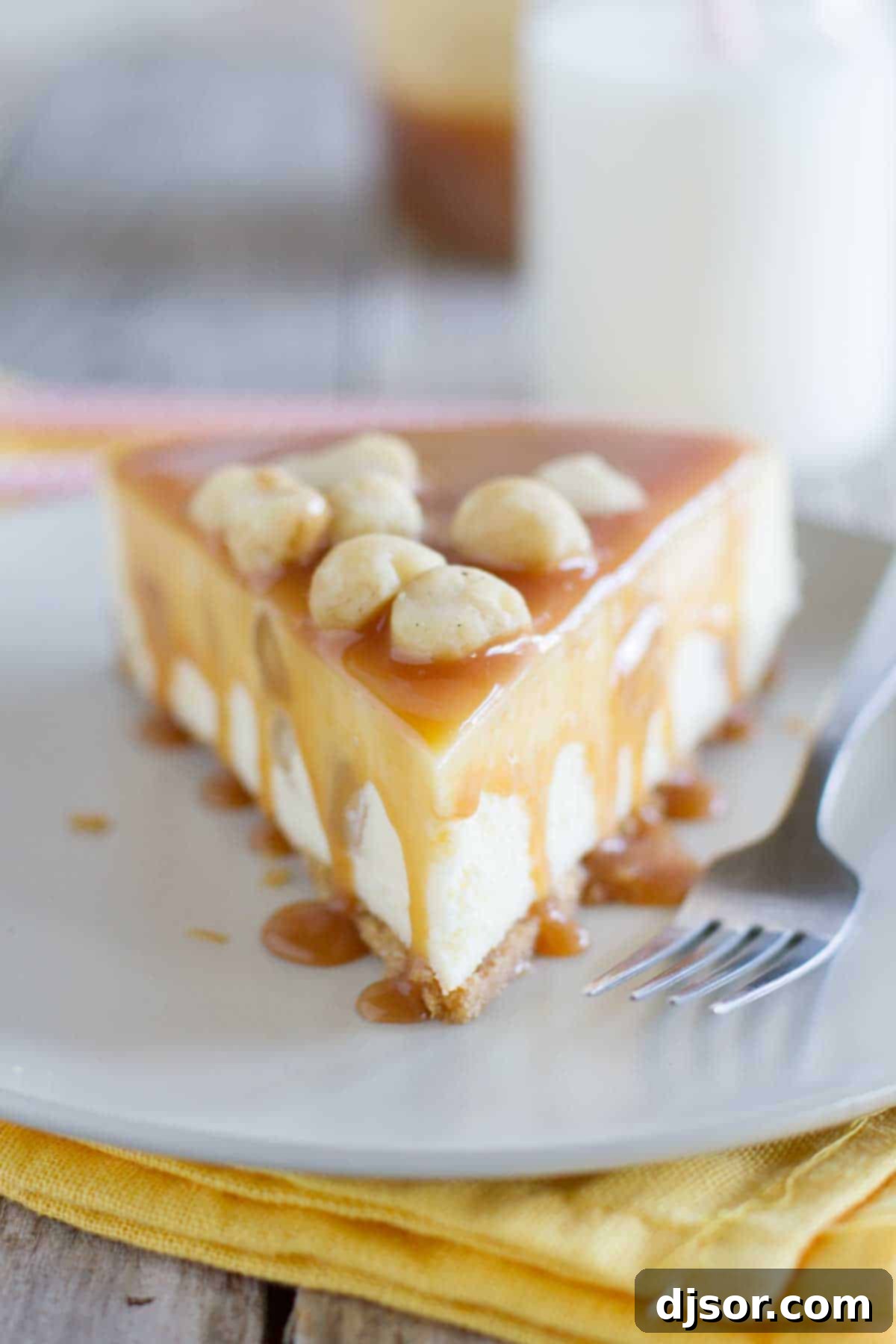 White Chocolate Cheesecake with Macadamia Nuts and Caramel - Creamy white chocolate cheesecake has macadamia nuts throughout, with a homemade caramel sauce poured over the top. A close-up view of a fork holding a delicious bite of white chocolate macadamia nut cheesecake, with rich caramel sauce dripping down, emphasizing its creamy texture.
