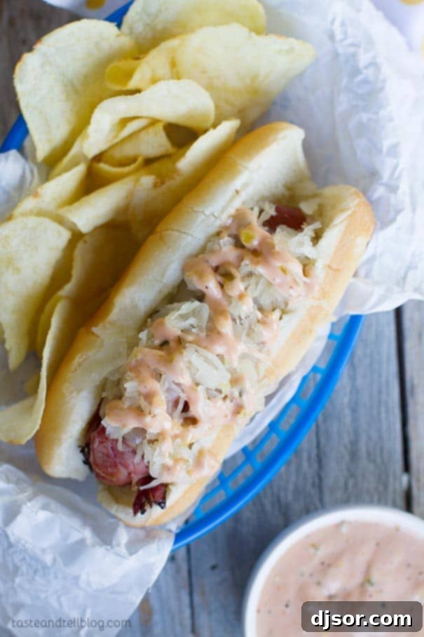 Pastrami Wrapped Hot Dog with sides A Pastrami Wrapped Hot Dog served in a basket with potato chips, garnished with fresh herbs.