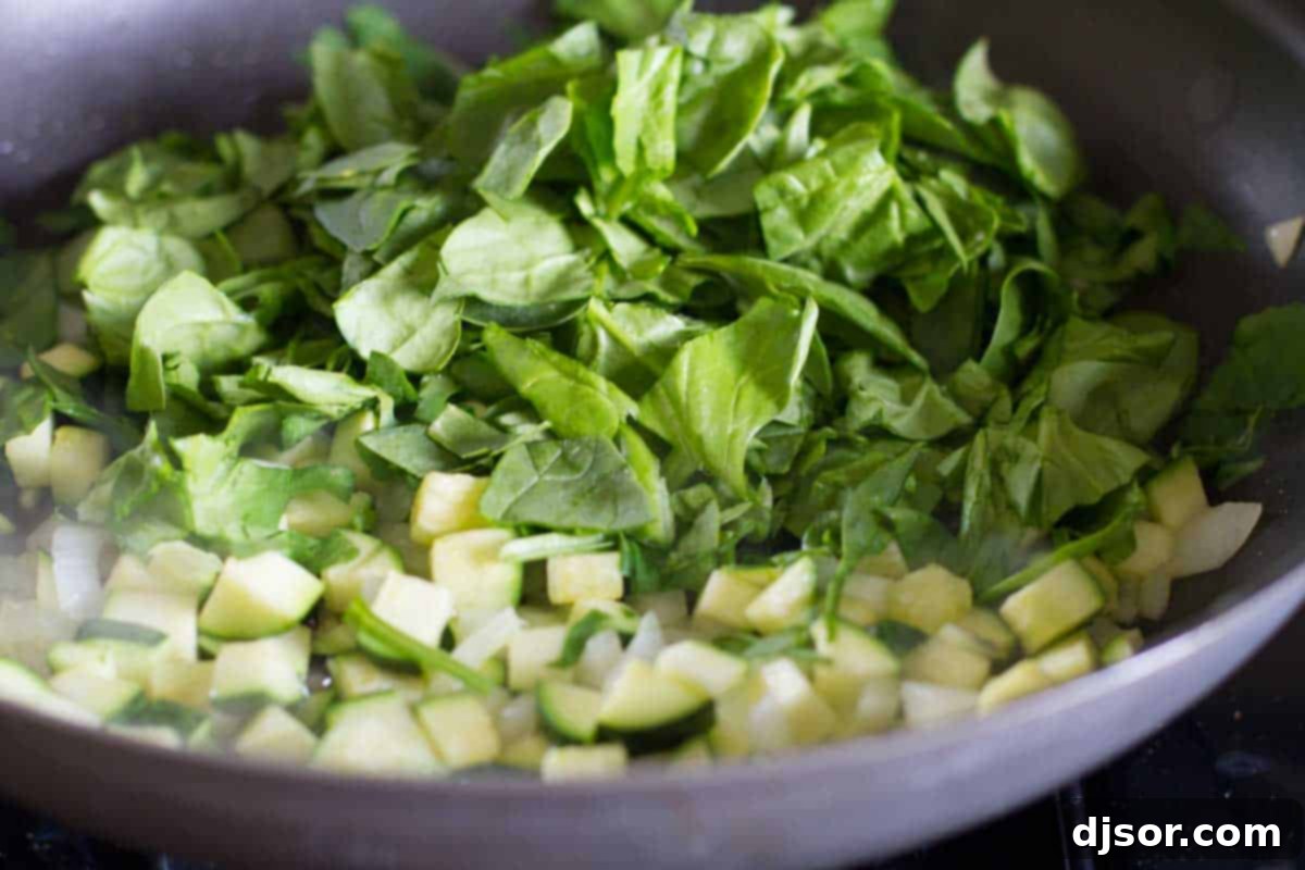 Cooking down fresh vegetables like zucchini and onions for the tomato filling.