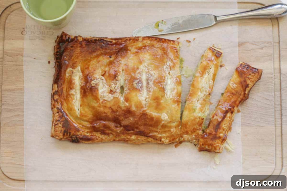 Golden brown puff pastry potato pie, filled with potatoes and leeks, resting on a wooden board.