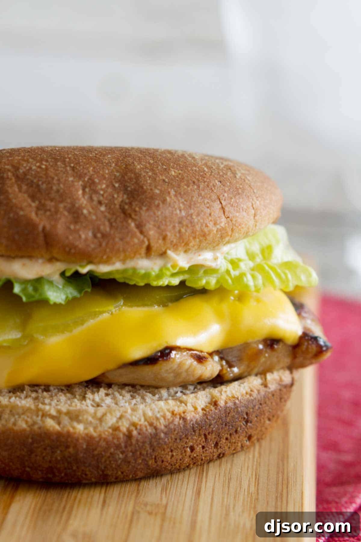 Close-up of a perfectly assembled Carl's Jr. Copycat Santa Fe Grilled Chicken Sandwich with melted cheese, green chile, and lettuce.