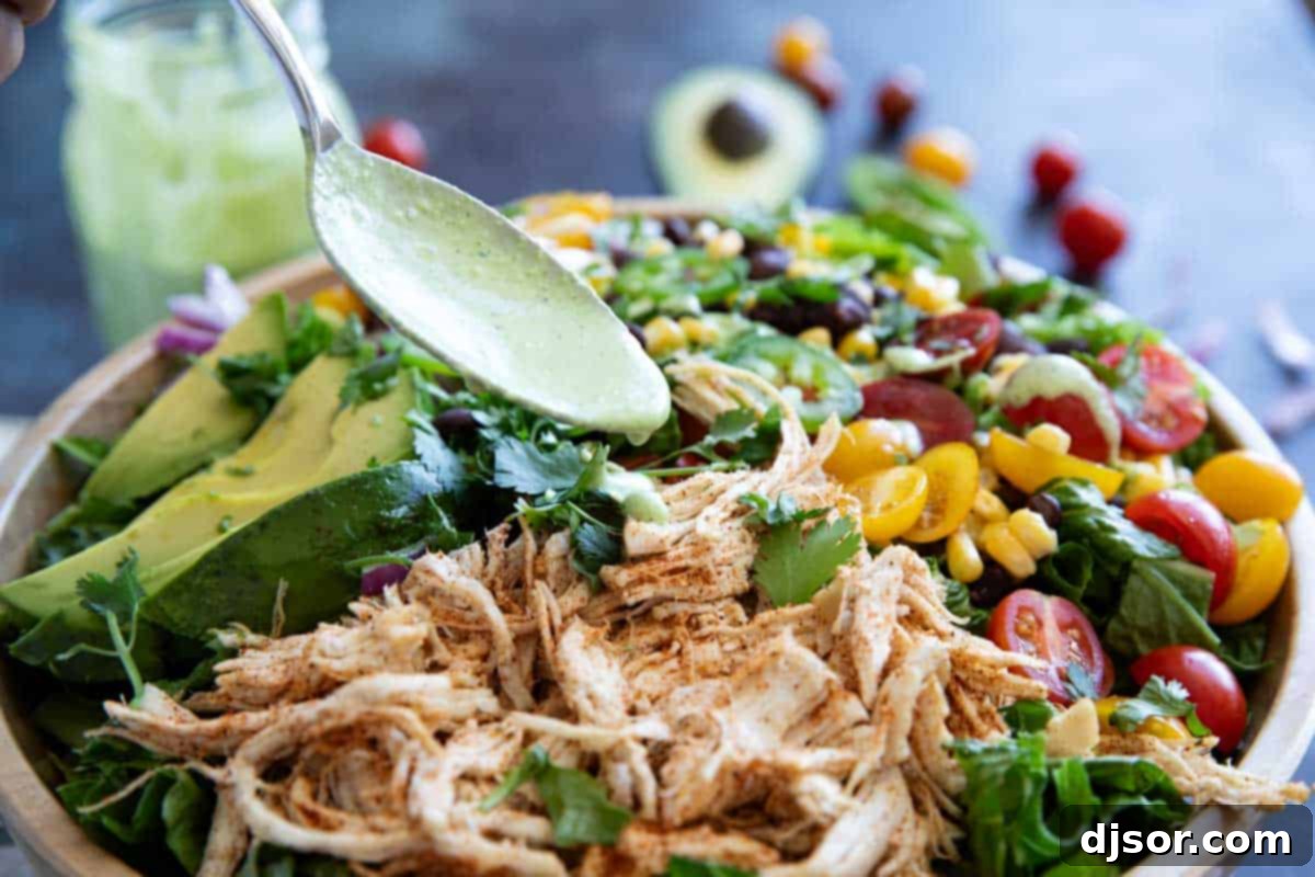 Spooning dressing ove a southwest chicken salad.