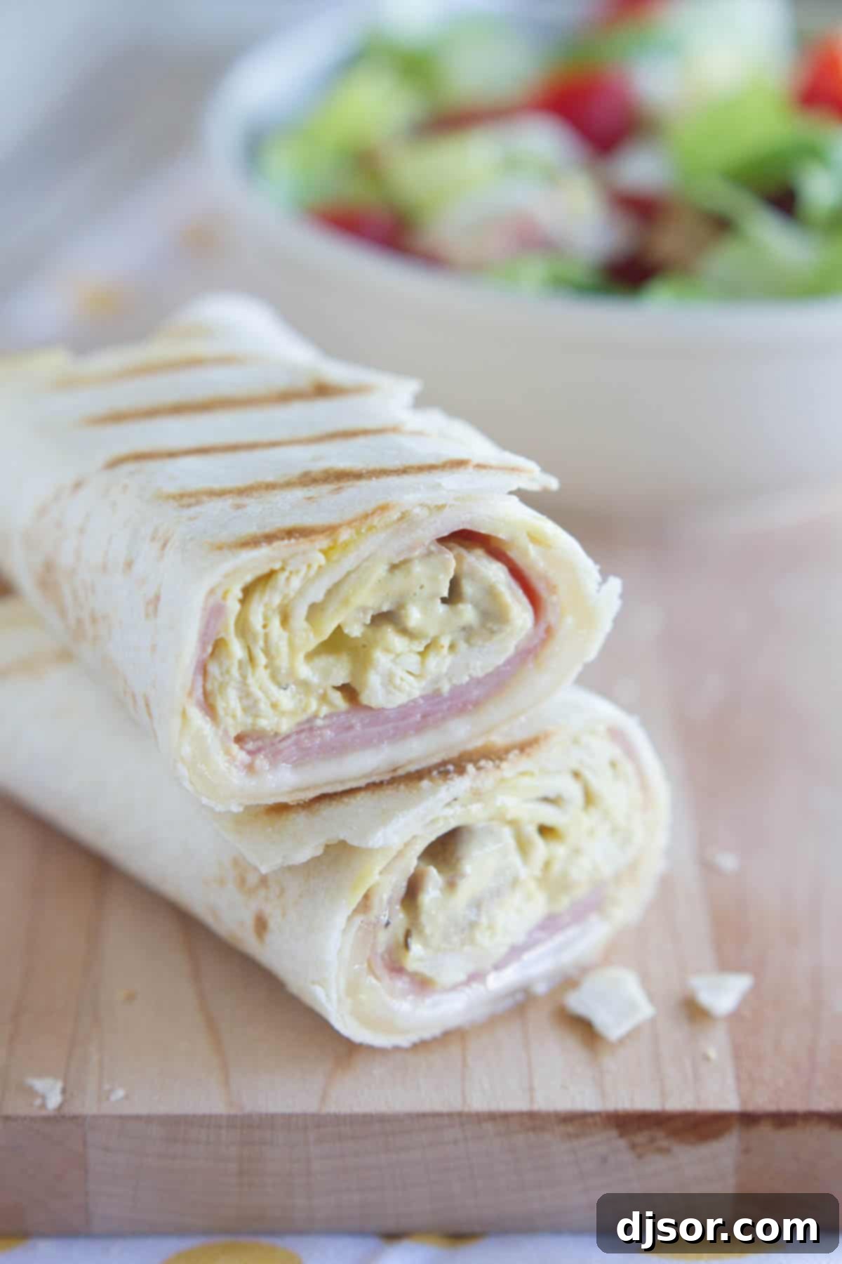 Cordon Bleu Grilled Chicken Wraps 2 Grilled Chicken Cordon Bleu Wrap cut in half to show interior with melted Swiss cheese, ham, and honey mustard coated shredded chicken.
