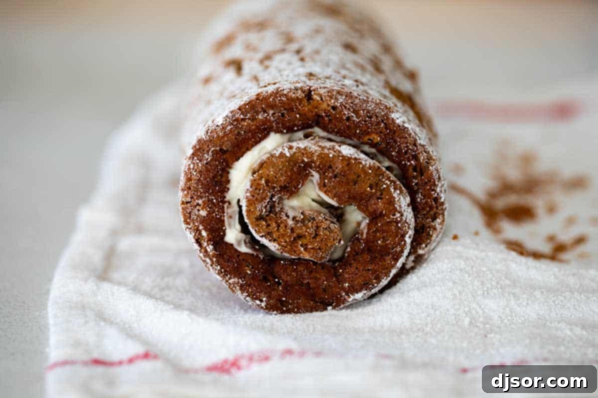 Rolled pumpkin cake on a tea towel, cooling for assembly.