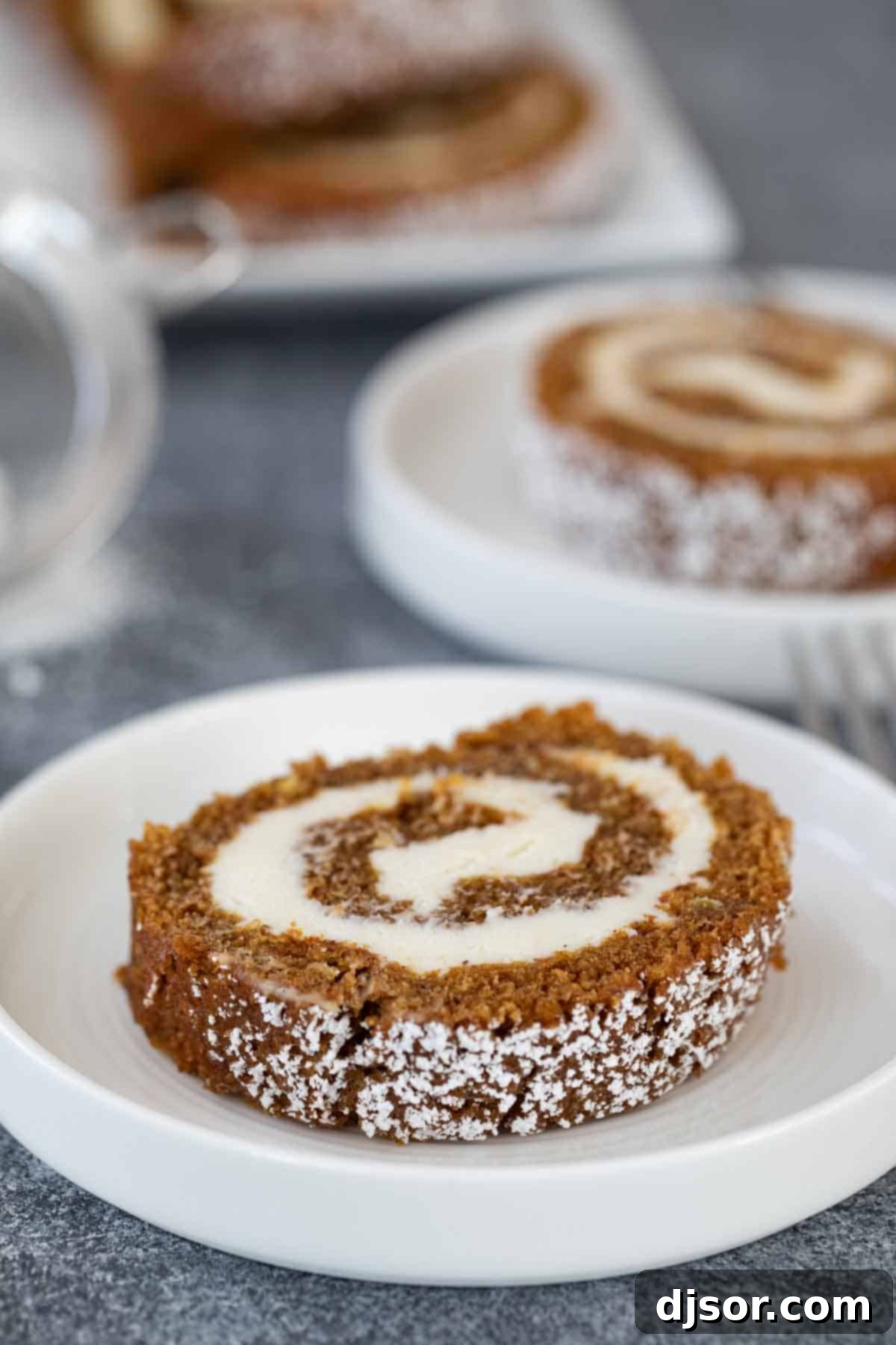 A single slice of pumpkin roll on a white plate, showcasing the filling swirls.