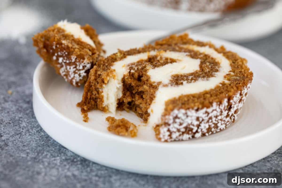 Close-up of a pumpkin roll slice, showing the moist cake and thick cream cheese filling.