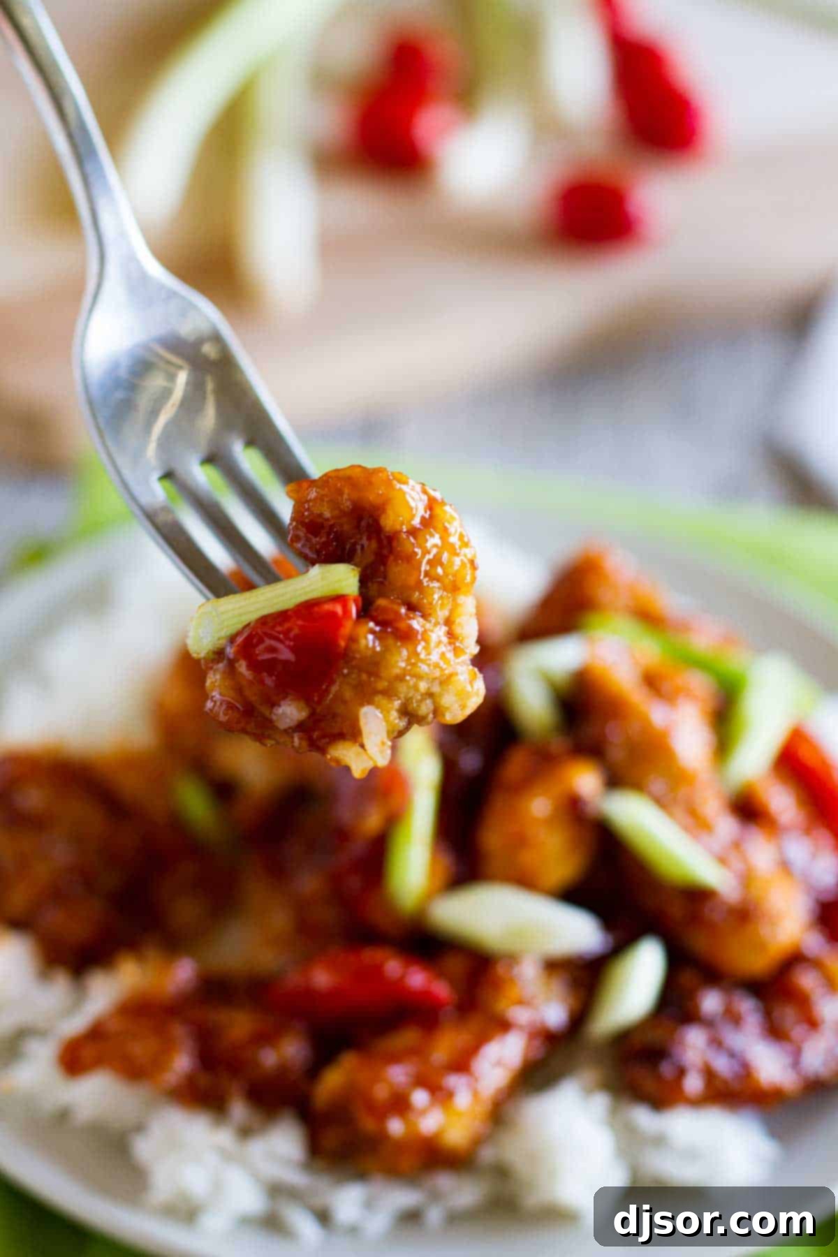 Wok-Kissed Chicken Delights 4 A single piece of crispy Chinese chicken held by a fork, showing its delicious texture and coating.