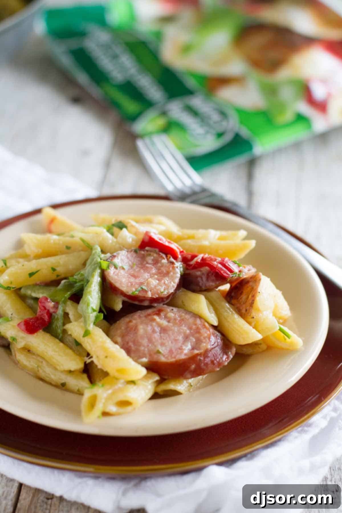 A single portion of Skillet Pasta with Sausage served on a white plate, garnished with fresh parsley.