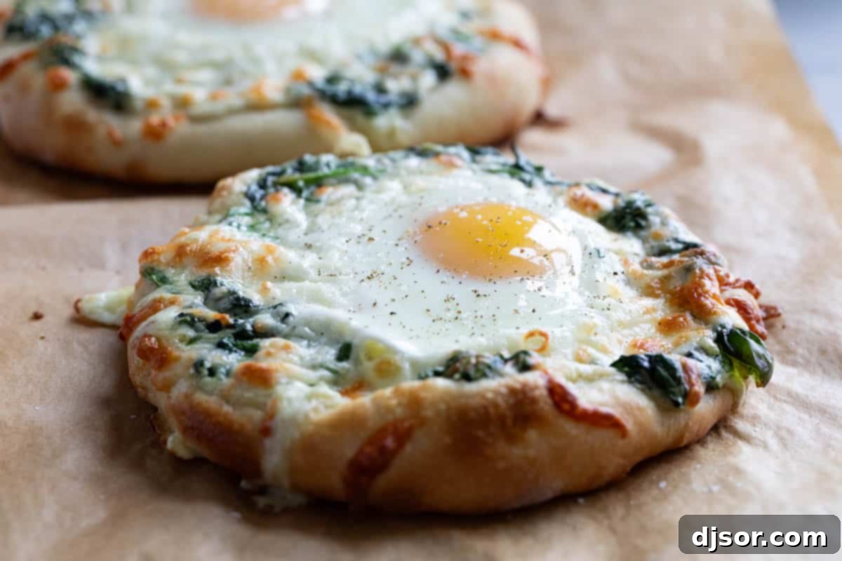 Breakfast meets dinner with this Egg Pizza with Creamed Spinach which tops pizza dough with creamed spinach and a perfectly cooked egg. Individual Egg Pizza topped with vibrant creamed spinach and a perfectly fried sunny side up egg, ready to be served.