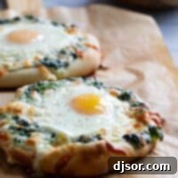 Ispanak Kremasıyla Zenginleştirilmiş Yumurta Pizzası 2 Two individual sized pizzas topped with creamed spinach and an egg on parchment paper.