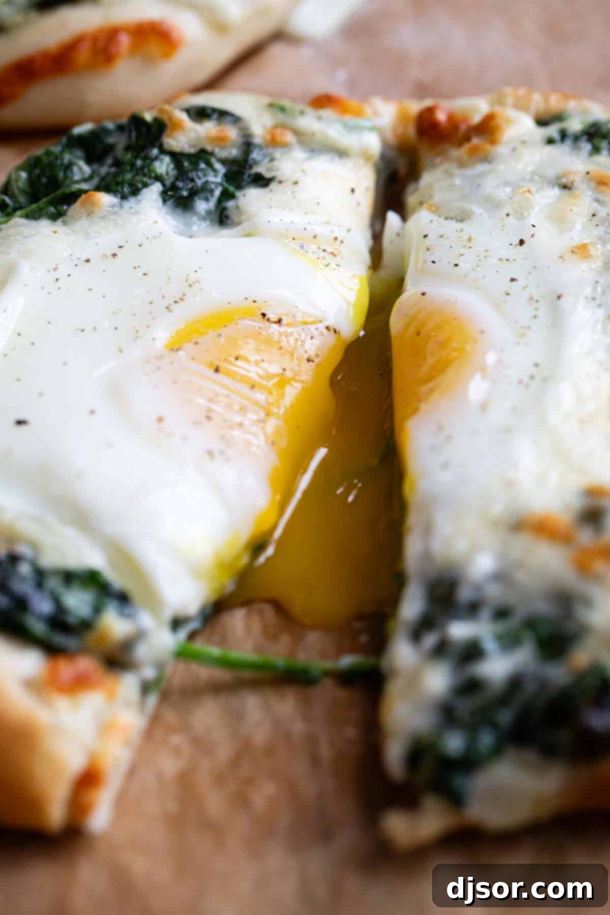 Breakfast meets dinner with this Egg Pizza with Creamed Spinach which tops pizza dough with creamed spinach and a perfectly cooked egg. A slice of egg pizza with creamed spinach, showcasing a perfectly runny egg yolk oozing out, inviting a delicious bite.