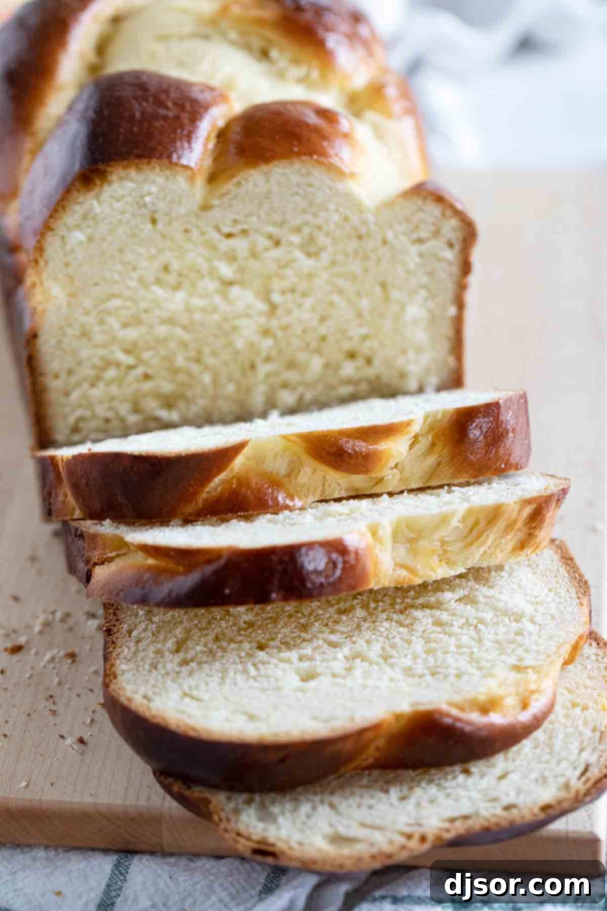 Several soft, airy slices of golden brioche bread neatly stacked on a wooden cutting board, ready for serving.