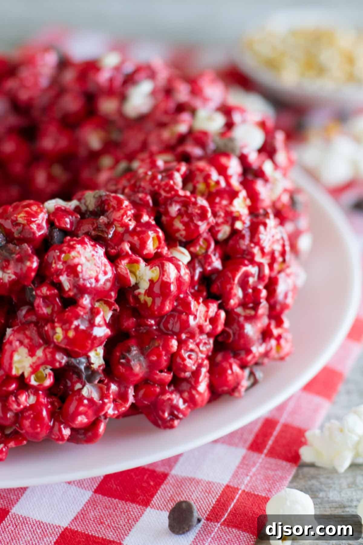 Decadent Red Velvet Popcorn Cake 2 Red Velvet Popcorn Cake on a plate, garnished with chocolate chips.