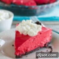 Slice of no bake red velvet cheesecake with the rest of the cheesecake in the background.