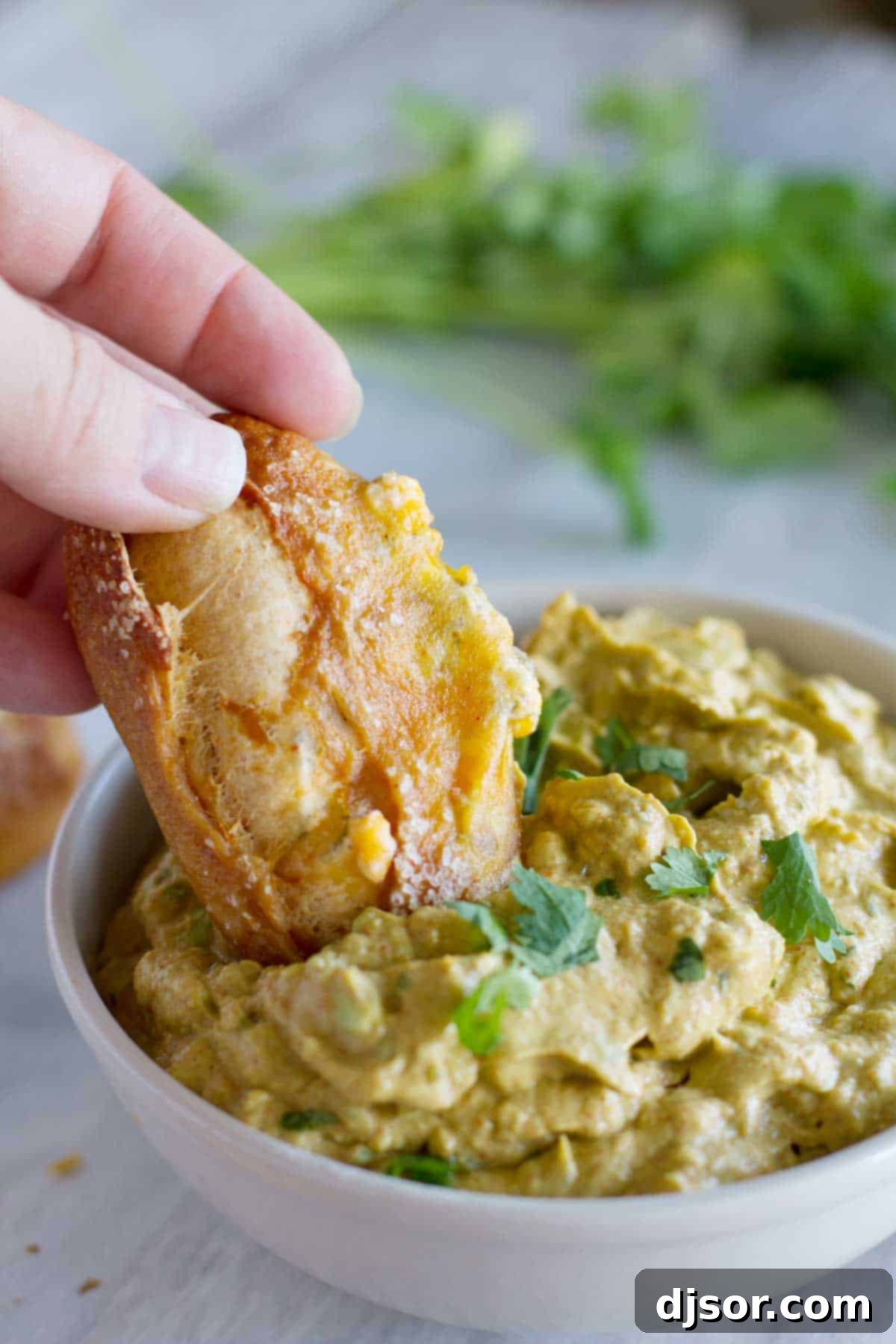 Spicy Taco Pretzel Sticks 8 A hand dipping a golden Jalapeño Stuffed Taco Soft Pretzel Stick into a creamy bowl of vibrant green guacamole, showcasing the perfect pairing.