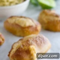 Jalapeno Stuffed Taco Soft Pretzel Sticks on parchment with guacamole for dipping in the background.