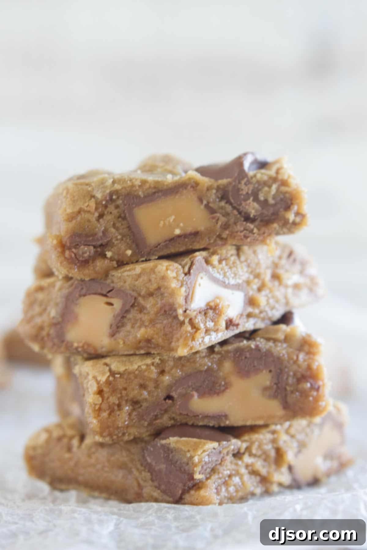 Four Spice Cake Caramel Blondies perfectly stacked on top of each other, showcasing their soft texture and gooey caramel centers.