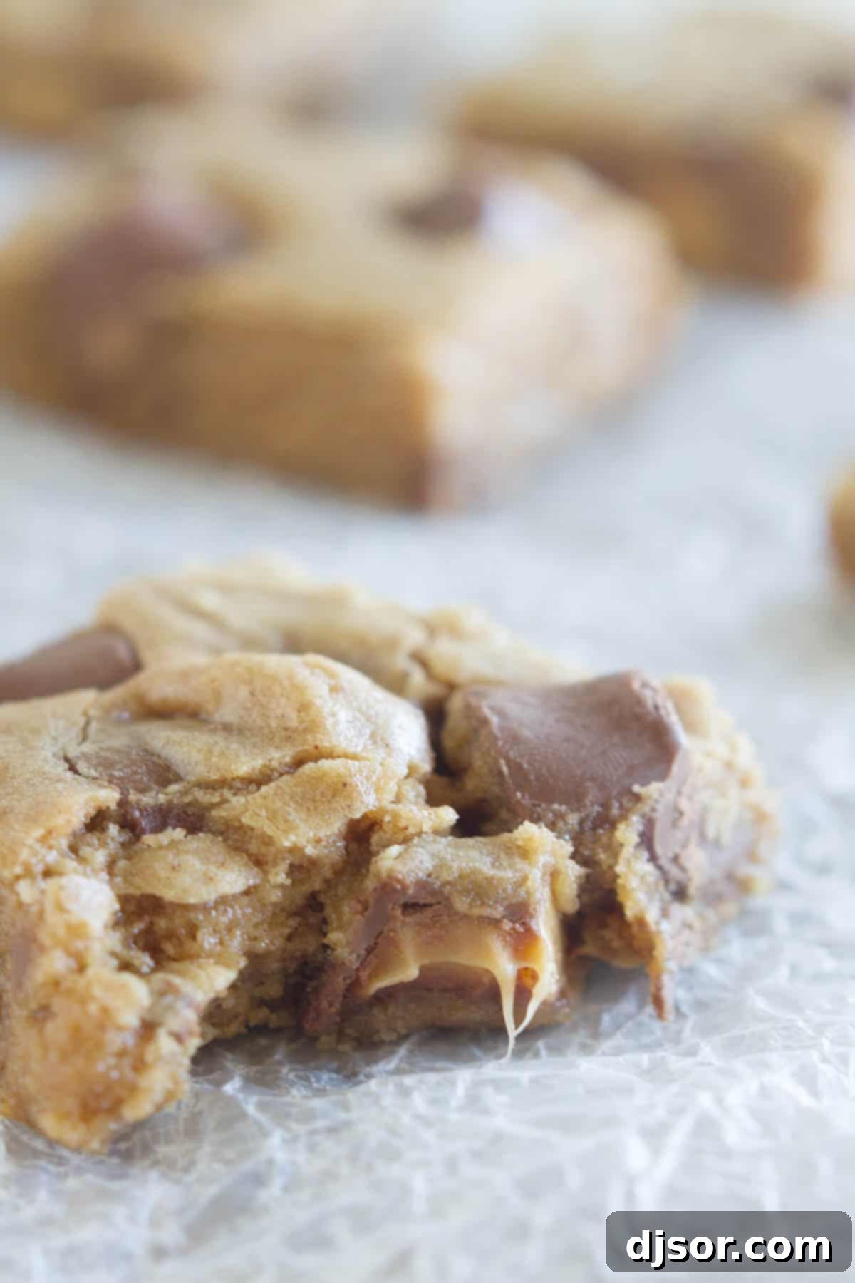 A close-up of a Spice Cake Caramel Blondie with a bite taken out of it, revealing its soft, moist interior and melted caramel.