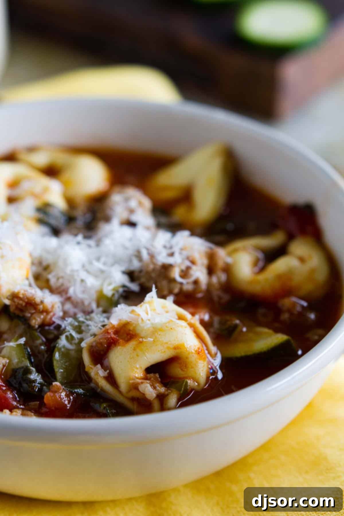 Close-up of Sausage Tortellini Soup in a pot, showing chunks of sausage, tortellini, and vibrant vegetables like spinach, zucchini, and carrots.