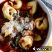 Bowl of Sausage Tortellini Soup topped with parmesan cheese.