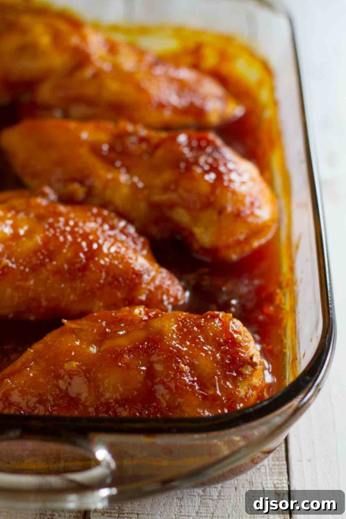 Caramelized Chicken Perfection 3 Several pieces of baked Candied Chicken soaking in its rich, sweet, and tangy sauce inside a baking dish, ready to be served.