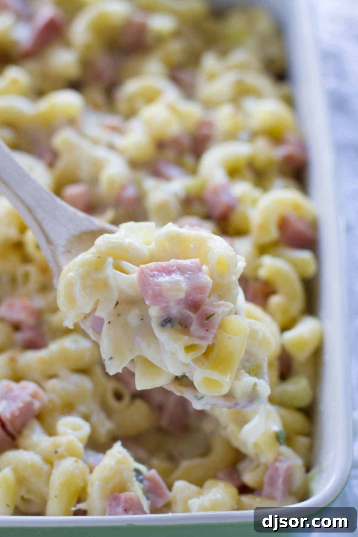 scooping out Mac and Cheese with Ham on a wooden spoon
